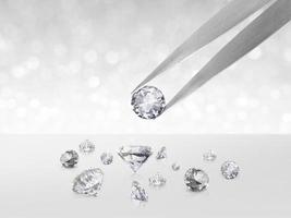 Diamond in tweezers on white shining bokeh background. concept for chossing best diamond gem design photo