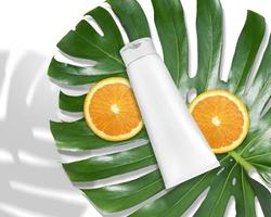 anuncio de productos de lujo para el cuidado de la piel, vista superior del tubo de plástico cosmético de embalaje en blanco con hojas de monstera y naranjas foto