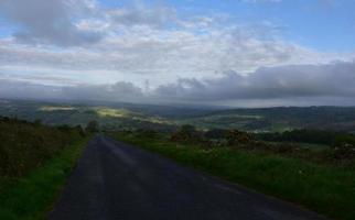 Wide Dirt Trek with Storm Clouds Hover Over Countryside photo