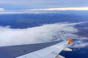 The wing of the aircraft against the background of the landscape with clouds photo