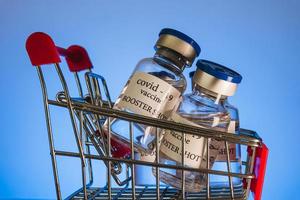 COVID-19 booster vaccine vials in shopping cart. Medicine and health care concept photo