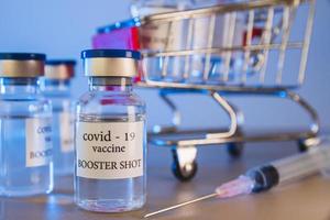 COVID-19 booster vaccine vials in shopping cart. Medicine and health care concept photo