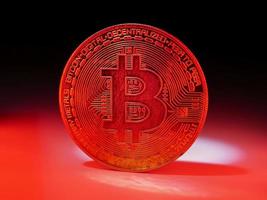 A coin with bitcoin symbol on red light. Concept of a cryptocurrency market crisis. photo