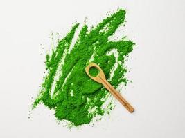 Top view of green powder and wooden spoon on white background. photo