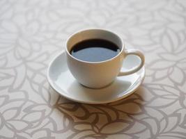 smoke on Black coffee in a white cup placed on a wooden table photo