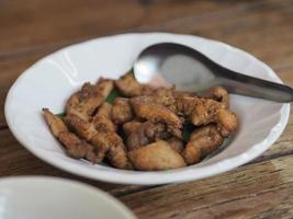 cerdo seco frito con hojas de lima kaffir fritas y repollo, finamente rebanado en plato negro, comida tailandesa, en plato blanco con cuchara foto