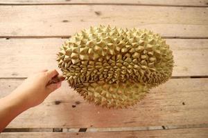 Durian, a large fruit laying on a brown plank floor. It is a fruit of Thailand that is abundant in summer. photo