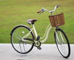 la bicicleta amarilla tiene una cesta de plástico marrón estacionada en el suelo de hormigón, borrosa de fondo natural foto