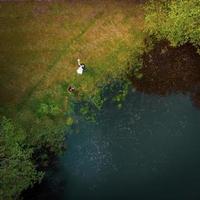 Tow down aerial view wedding photo shoot beautiful couple by lake outdoors. Wonderful wedding in nature In Lithuania