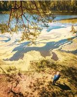 Top down view senior woman stand holding nordic sticks and enjoy panoramic view of lake in sunny beautiful day. Texture and nature well-being concept background photo