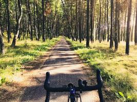 vista frontal bicicleta de carretera manijas de bicicleta con fondo de árbol forestal en forma de ruta de asador curoniano. famoso destino de vacaciones en bicicleta en lituania foto