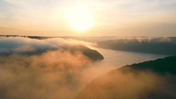 Side view of beautiful scenery of mist river valley at sunset. Panoramic view of picturesque valley with meandering foggy river flowing between hills with sunset on background. Concept of landscape video