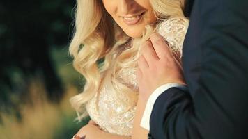 Crop view of blond hair bride and groom holding hands, hugging on their wedding day. Close up view of wedding couple gentle holding hands, bride smiling, her ring is visible. Concept of wedding video