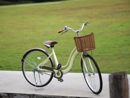 Yellow Bicycle has Basket of brown plastic parked on concrete floor, blurred of nature background photo