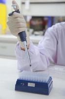 Woman scientist biochemist at the workplace makes the analysis in the modern laboratory. She is holding a dropper and a test tube photo