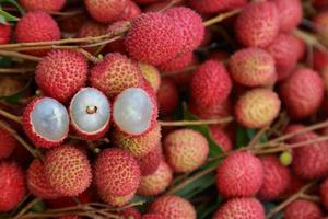 Lychee, Fresh lychee and peeled showing the red skin and white flesh with green leaf . photo