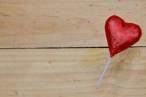 Chocolate heart wrapped in red  on wood. valentine concept. Space for text. photo