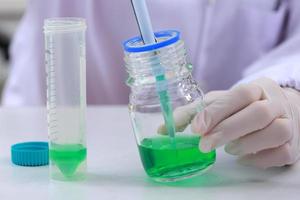 Woman scientist biochemist at the workplace makes the analysis in the modern laboratory. She is holding a dropper and a test tube photo