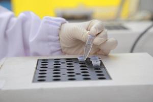 mujer científica bioquímica en el lugar de trabajo hace el análisis en el laboratorio moderno. ella está sosteniendo un gotero y un tubo de ensayo foto