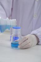 Woman scientist biochemist at the workplace makes the analysis in the modern laboratory. She is holding a dropper and a test tube photo