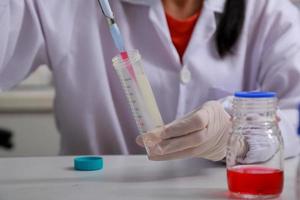 Woman scientist biochemist at the workplace makes the analysis in the modern laboratory. She is holding a dropper and a test tube photo