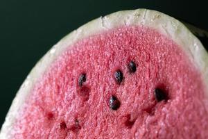 A half of fresh watermelon on dark background. Close-up macro photo. Fresh fruits texture. High quality photo