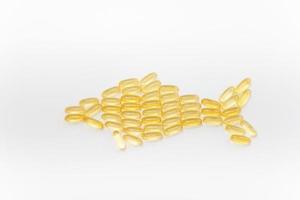 Fish shape Cod Liver Oil Capsules, Omega 3, Vitamin D on white background. Close-up, top view, copy space for your text. photo