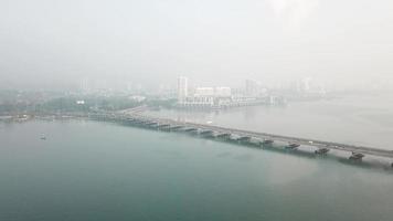 Fly toward Penang Bridge with background The Light condo in misty morning. video