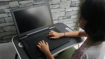 Closeup image of a little girl working and typing on laptop computer keyboard photo