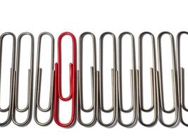 Metal paper clips on a white background. Office supplies isolate. Idea. The concept of loneliness. Confrontation. Stands out from the crowd. photo