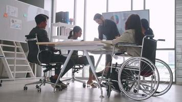 een gehandicapte medewerker van het bedrijf kan prettig samenwerken met collega's op kantoor. een groep marketeers heeft een discussie op de bijeenkomst.