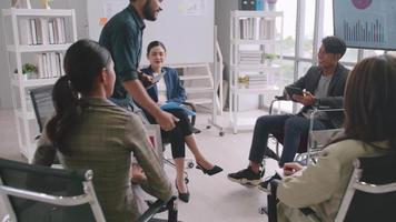 Confident businessman in wheelchair shaking hands with colleague in meeting room. video