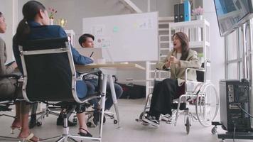 zelfverzekerde zakenvrouw in rolstoel presenteren tijdens zakelijke bijeenkomst met collega's.