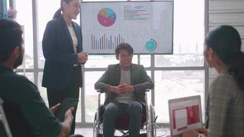 zelfverzekerde zakenman in rolstoel presenteren tijdens zakelijke bijeenkomst met collega's. video
