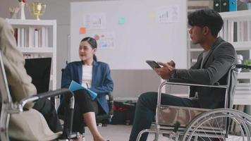 hombre de negocios confiado en silla de ruedas que presenta durante una reunión de negocios con colegas. video