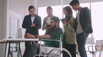 un employé handicapé de l'entreprise explique un programme informatique à un groupe de collègues. video