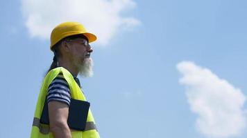 havenarbeider met een baard in een gele helm staat met een tablet-pc. de voorman inspecteert. 4k video