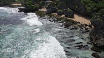 vista aérea da praia tropical em gunung kidul, indonésia com penhasco verde e rochoso. video