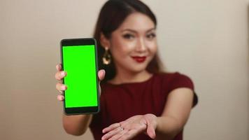 mujeres asiáticas jóvenes felices y sonrientes que muestran una pantalla en blanco verde. video