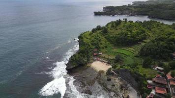 vista aérea da praia tropical em gunung kidul, indonésia com penhasco verde e rochoso. video