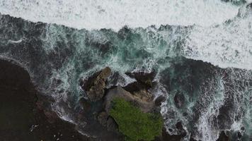 vista aérea de arriba hacia abajo de las olas gigantes del océano rompiendo y haciendo espuma en la playa de coral