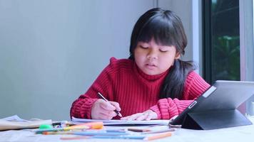 Asian girl sitting at home coloring pictures. video