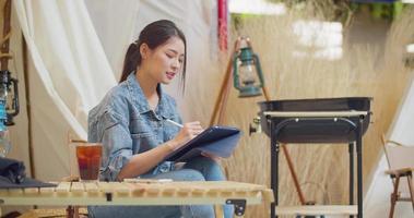 een mooie aziatische vrouw schildert graag op een tablet. 4k dci het ingediende beeldmateriaal is een groepsopname-arrangement video