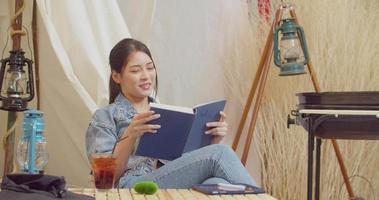 uma linda mulher asiática está feliz em ler um livro. 4k dci a filmagem enviada é um arranjo de filmagem de agrupamento video