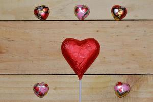 Chocolate heart wrapped in red  on wood. valentine concept. Space for text. photo