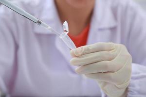 mujer científica bioquímica en el lugar de trabajo hace el análisis en el laboratorio moderno. ella está sosteniendo un gotero y un tubo de ensayo foto