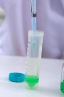 Woman scientist biochemist at the workplace makes the analysis in the modern laboratory. She is holding a dropper and a test tube photo