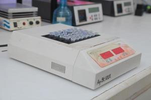 Woman scientist biochemist at the workplace makes the analysis in the modern laboratory. She is holding a dropper and a test tube photo