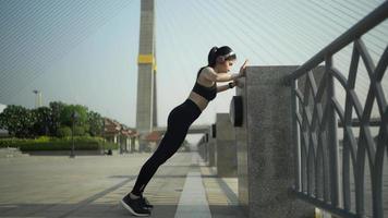 giovane donna sportiva che fa esercizi di stretching. ragazza che riposa dopo l'esercizio all'aperto. donna atletica che si estende contro un albero. sportiva in forma che fa esercizi di riscaldamento video