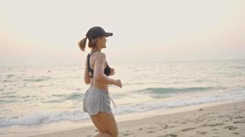 woman running ocean beach. Young asian female exercising outdoors running seashore. Concept of healthy running and outdoor exercise. Active, sporty athlete jogging. Summer active video